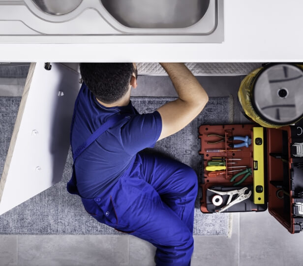 Plumber working underneath bathroom sink